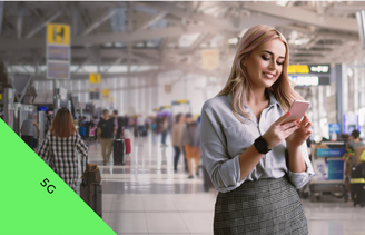 Image of smiling woman looking at her phone in busy airport