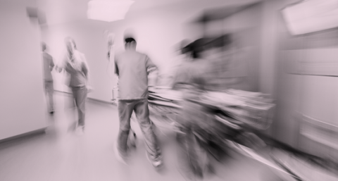 Blurred image of staff pushing a hospital bed